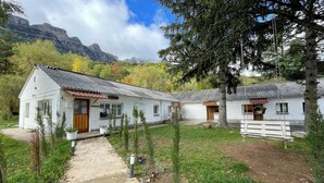 A rustic cabin with a metal roof, a wooden door, and a small porch. - Complejo Bubal Formigal 3000 (Biescas)