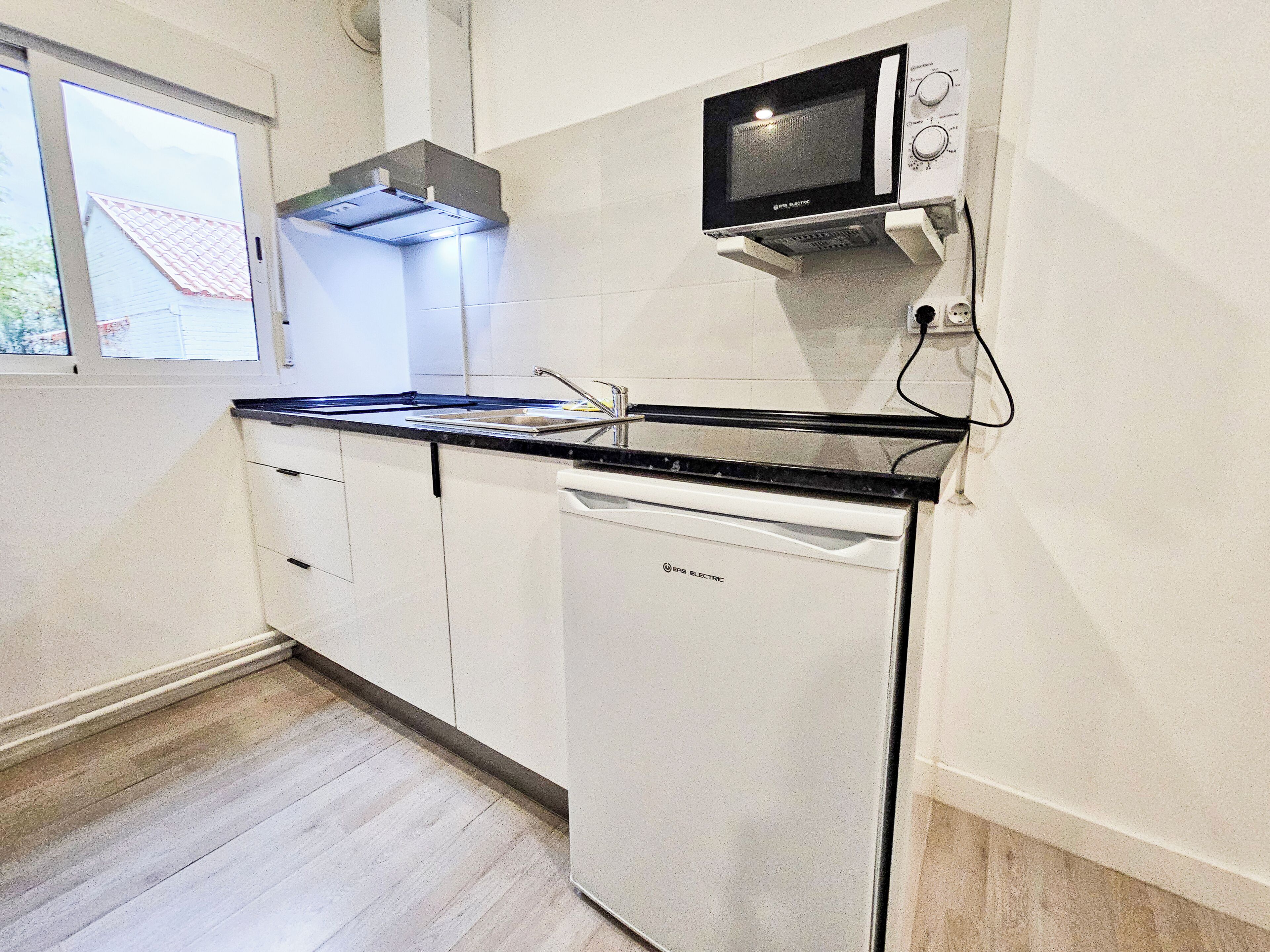 A compact kitchen with a built-in microwave, a dishwasher, and a window providing natural light.