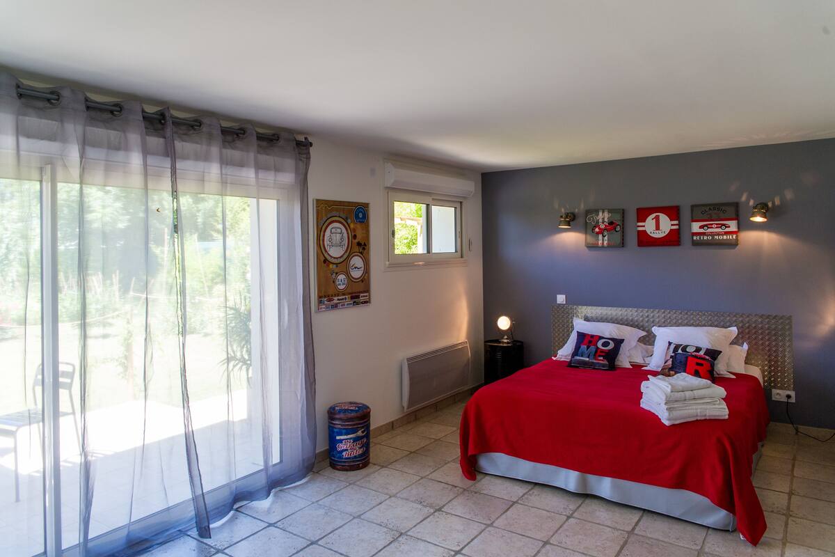 A bedroom with a bed, a window, a radiator, and wall decorations.