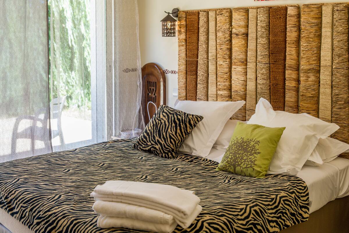 A bed with zebra-patterned bedding, a wooden headboard, and a green pillow with a tree design.