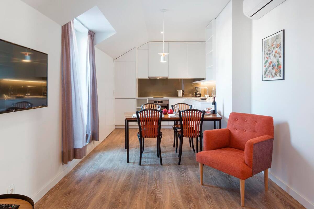Un apartamento moderno con comedor, cocina y un sillón rojo.