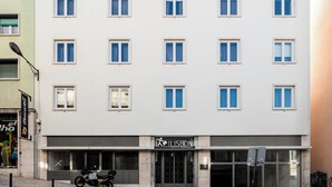 A modern building with a flat facade, multiple windows, and a ground-level entrance with a sign for serviced apartments.