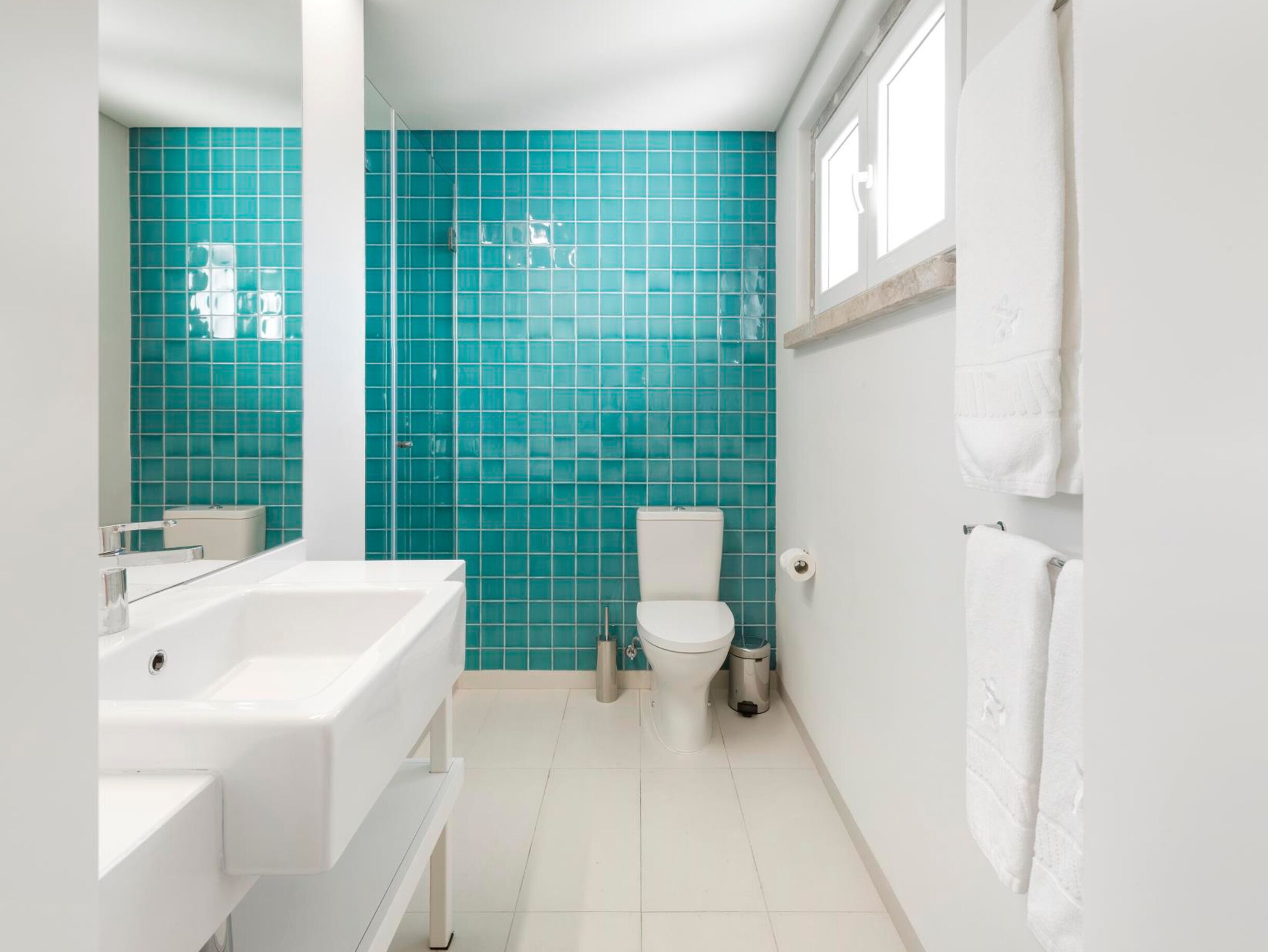 A bathroom with a white sink, toilet, and a large mirror.