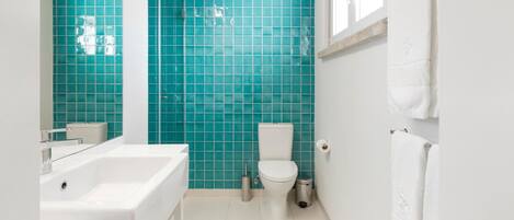 Une salle de bain avec un lavabo blanc, des toilettes et un grand miroir.