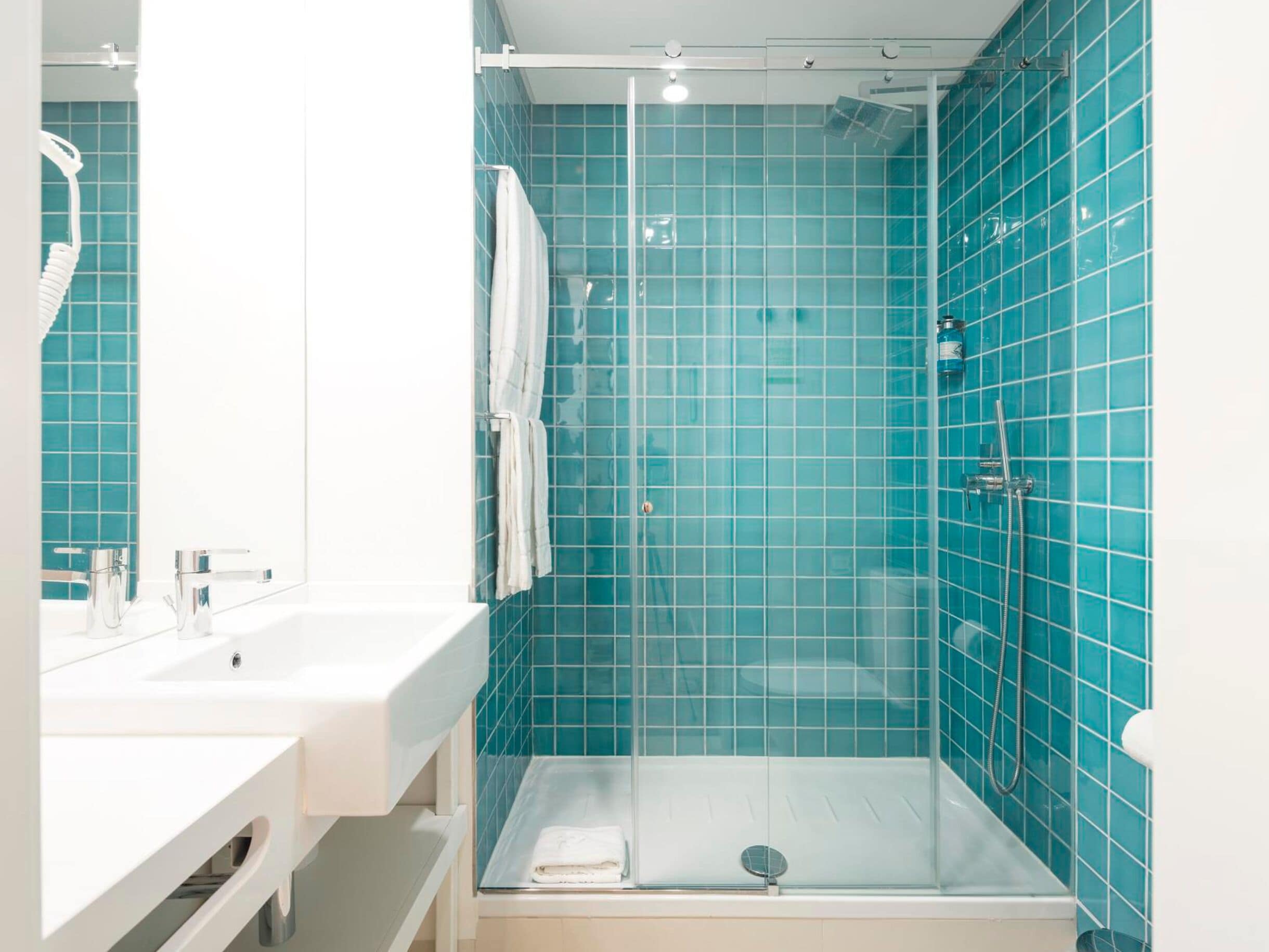 Une salle de bain moderne avec une douche à parois de verre, un lavabo blanc et un miroir.