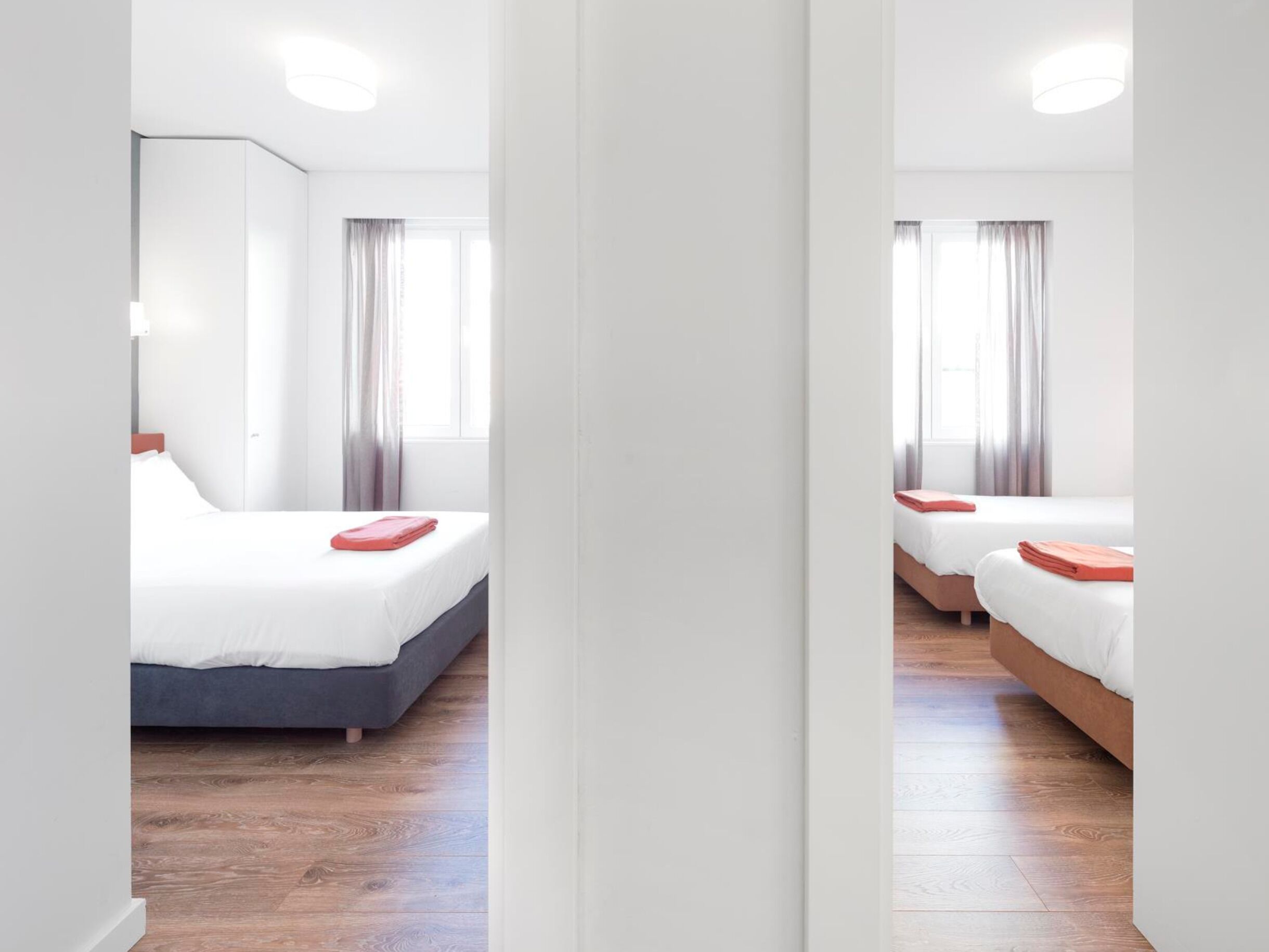 Ein Hotelzimmer mit einem großen Bett, einem kleineren Bett und einem Schreibtisch.