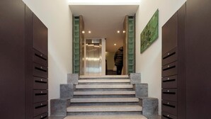 A staircase leading to an elevator in a modern building with dark wooden cabinets on either side.