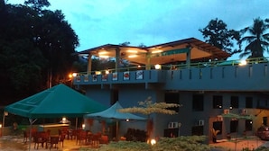 Un edificio de dos pisos con un espacio de estar techado al aire libre y un balcón.