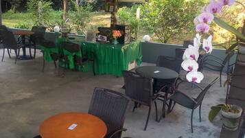 An outdoor patio area with tables and chairs, a reception desk, and a TV screen.