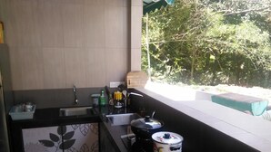 Cocina compacta con lavamanos, cocina y ventana con vistas a un jardín.