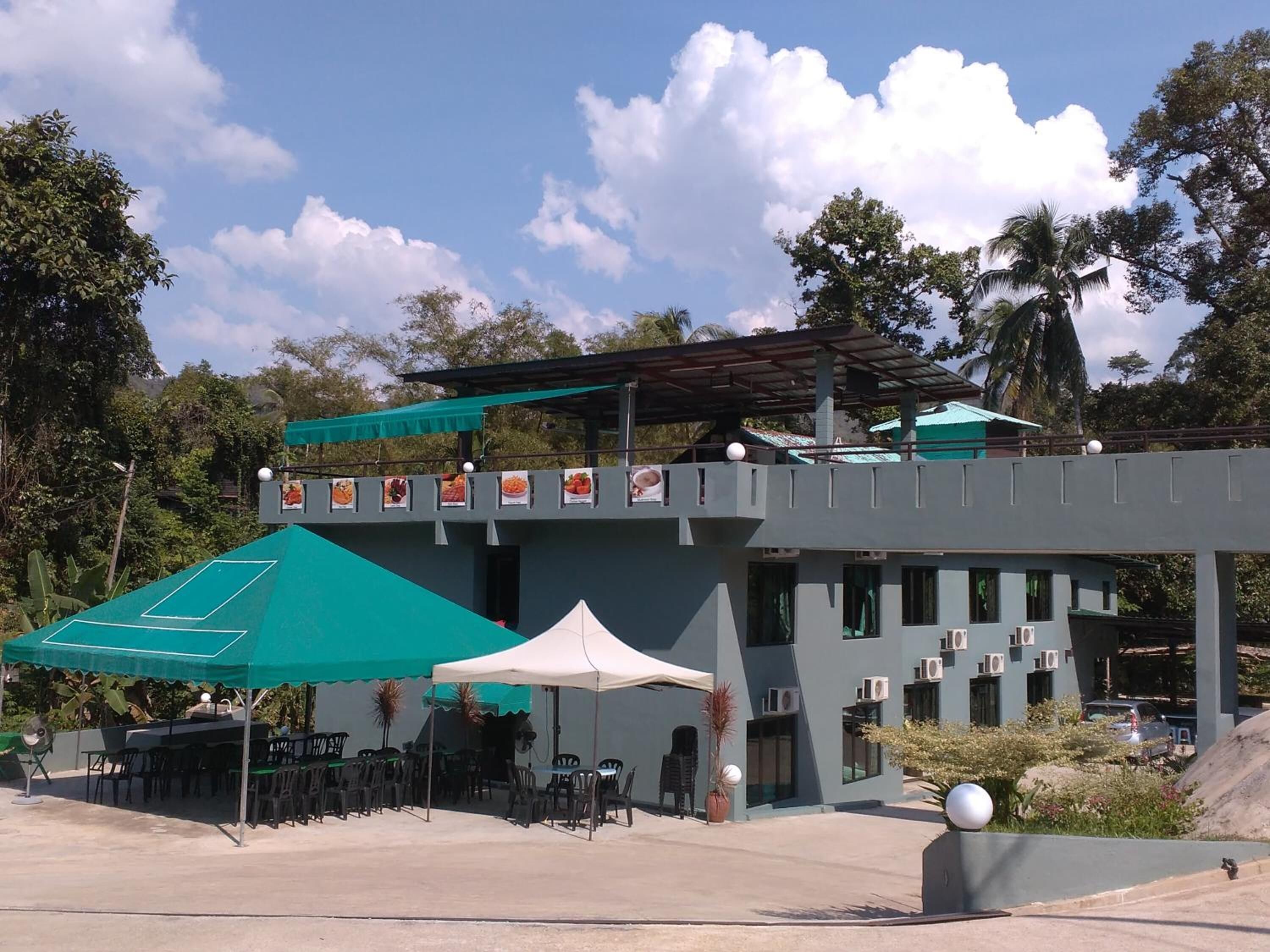 A two-story building with a flat roof, outdoor seating area with tables and chairs, and a covered patio.
