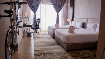 A hotel room with a bed, a desk, a chair, and a bicycle.