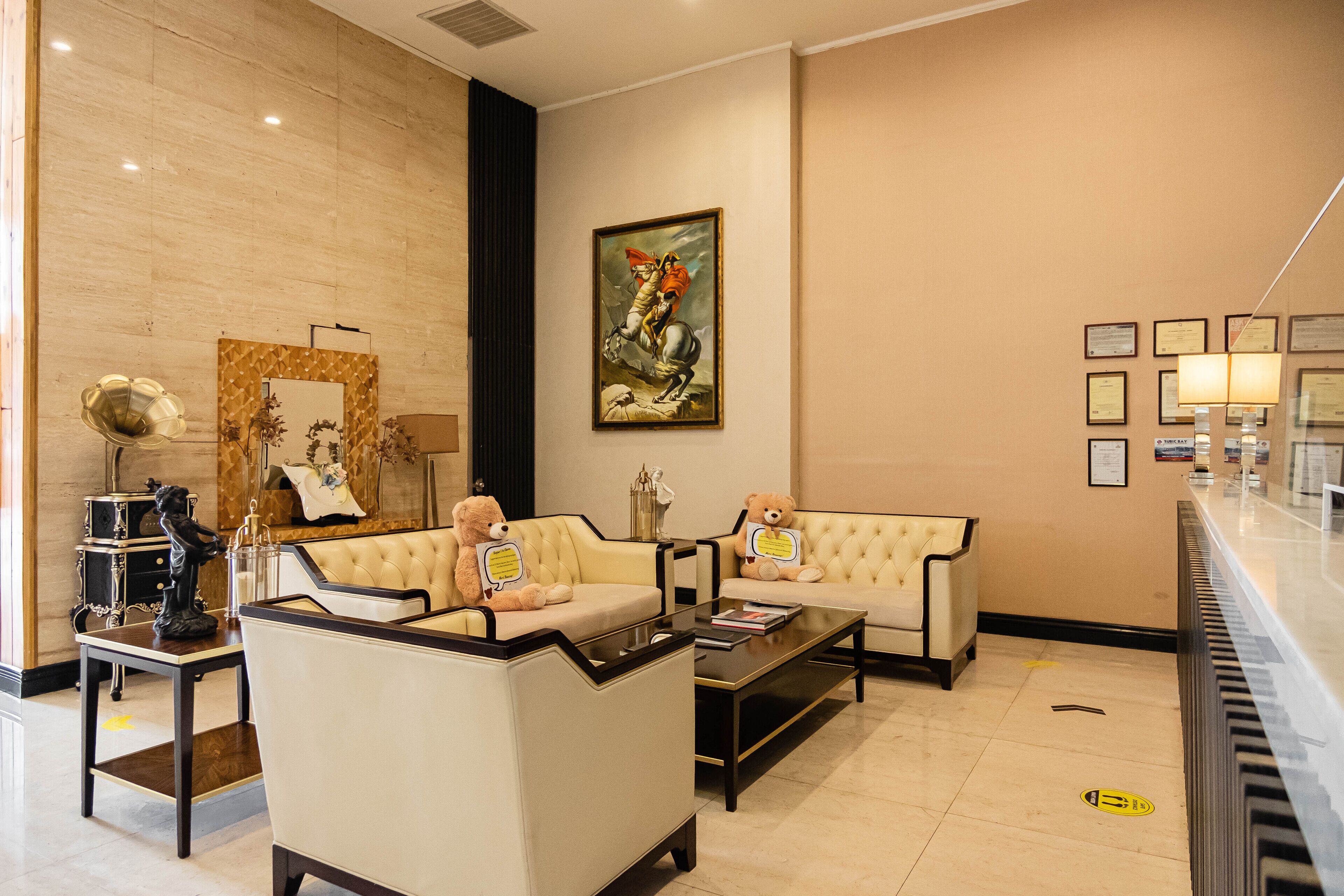 Um hall com dois sofás, uma mesa de centro, uma estátua e certificados emoldurados na parede.