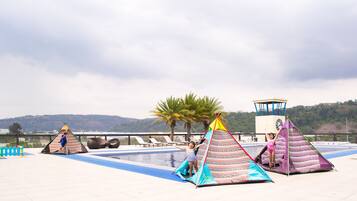 A rooftop pool area with three colorful tents and a lifeguard tower.