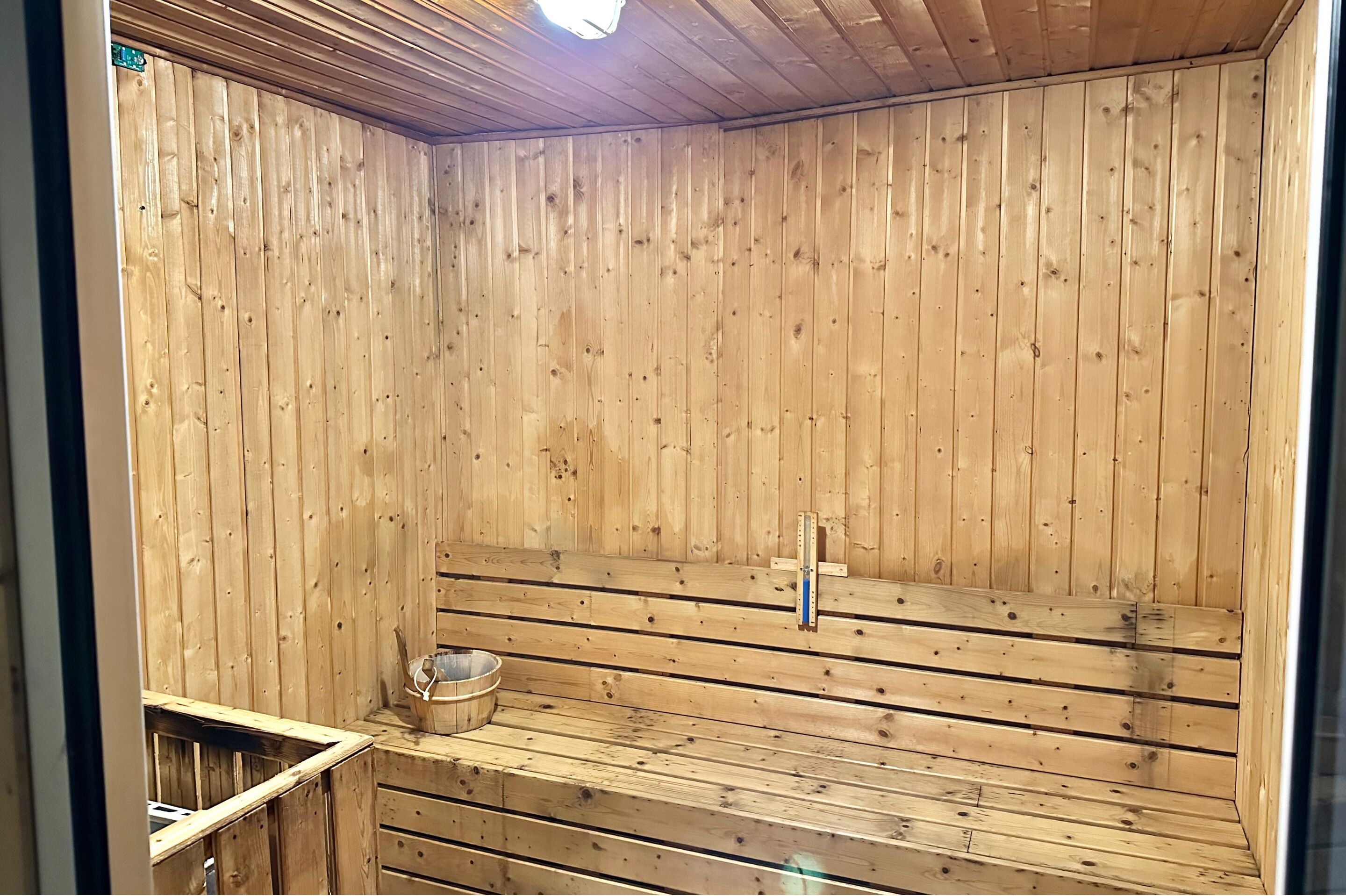 Eine Holzzimmer-Sauna mit Bänken und einem Metallbecken.