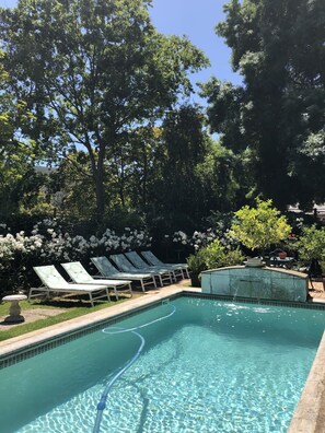 Una piscina al aire libre, sombrillas, sillones reclinables de piscina