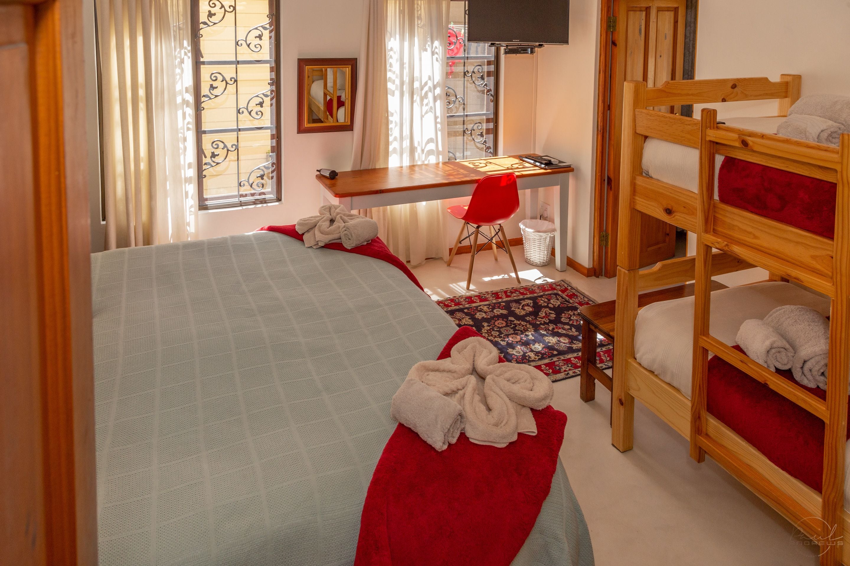 A room with a bed, a desk, a chair, and a bunk bed.