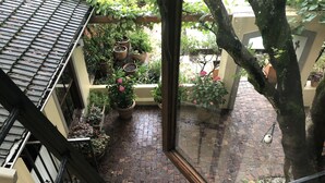 A courtyard with a brick floor, potted plants, and a view of the surrounding buildings. - 10 Alexander B&B (Stellenbosch)