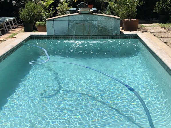 A rectangular swimming pool with clear water, surrounded by a tiled edge and a small fountain structure in the center. - 10 Alexander B&B (Stellenbosch)