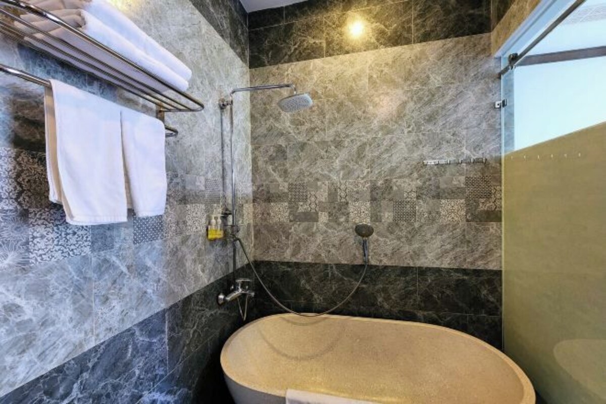 A modern bathroom with a freestanding bathtub, a towel rack with folded towels, and a shower area with a handheld showerhead.