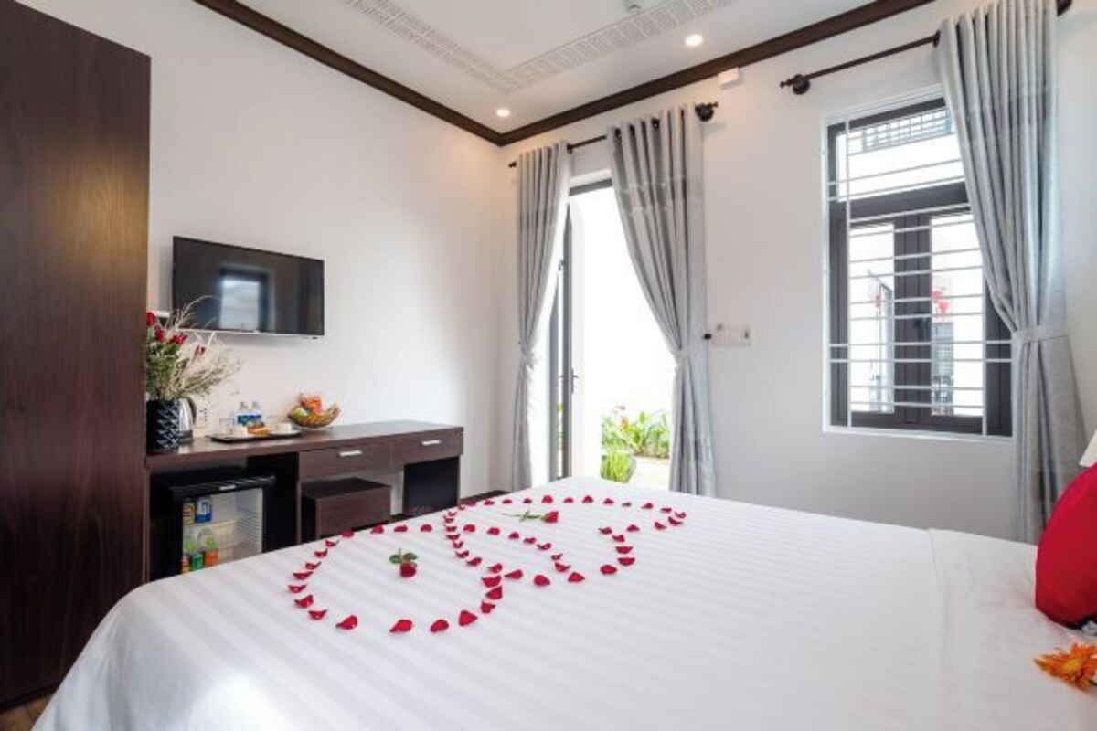 A hotel room with a bed, a desk, a television, and a window with curtains.