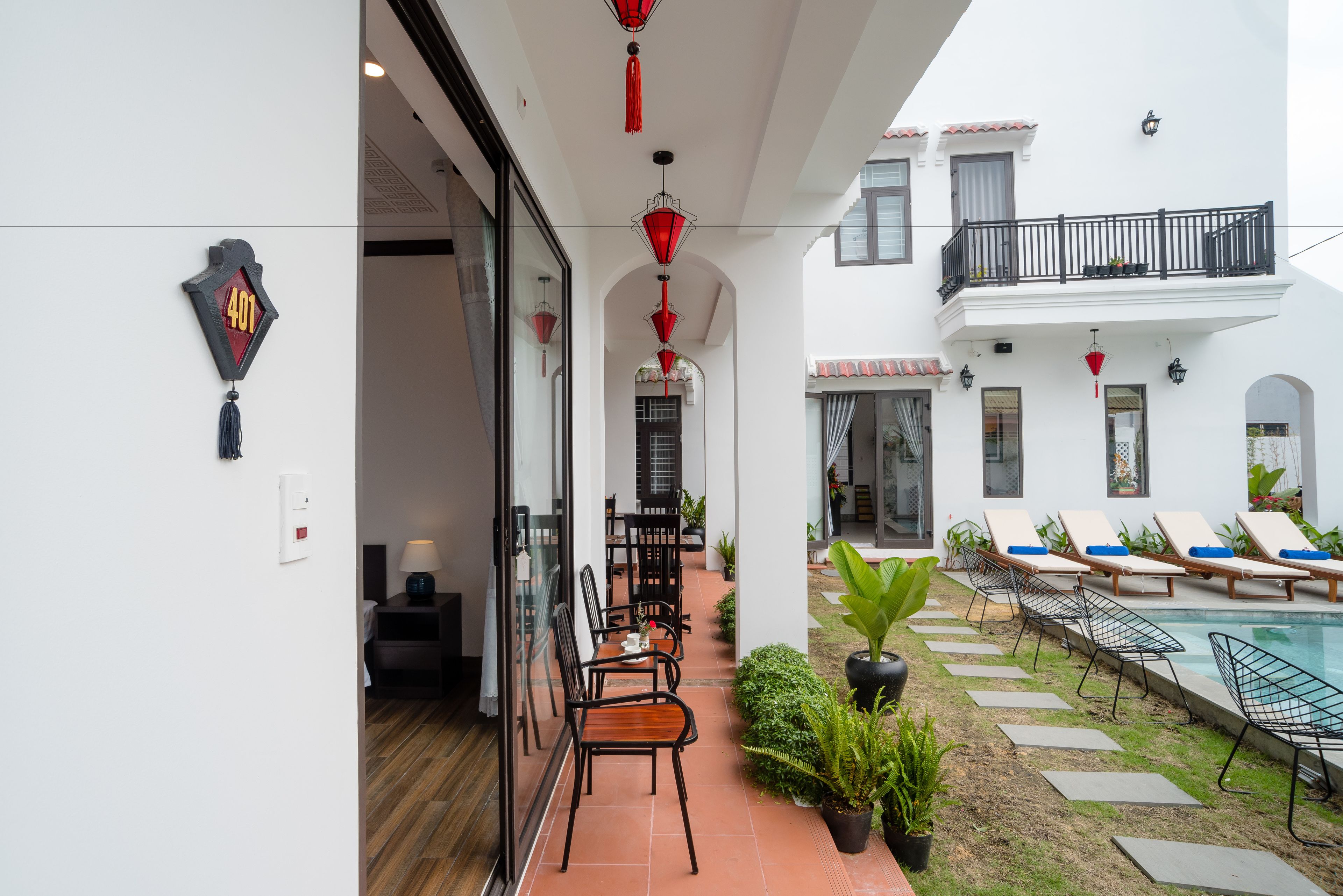A courtyard with a pool, lounge chairs, and a dining area with chairs and tables.