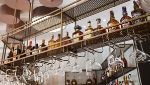Zona de bar con estantes llenos de botellas de licor y copas de vino colgando.
