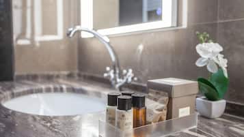 A bathroom with a marble sink, a mirror, and a small potted orchid.