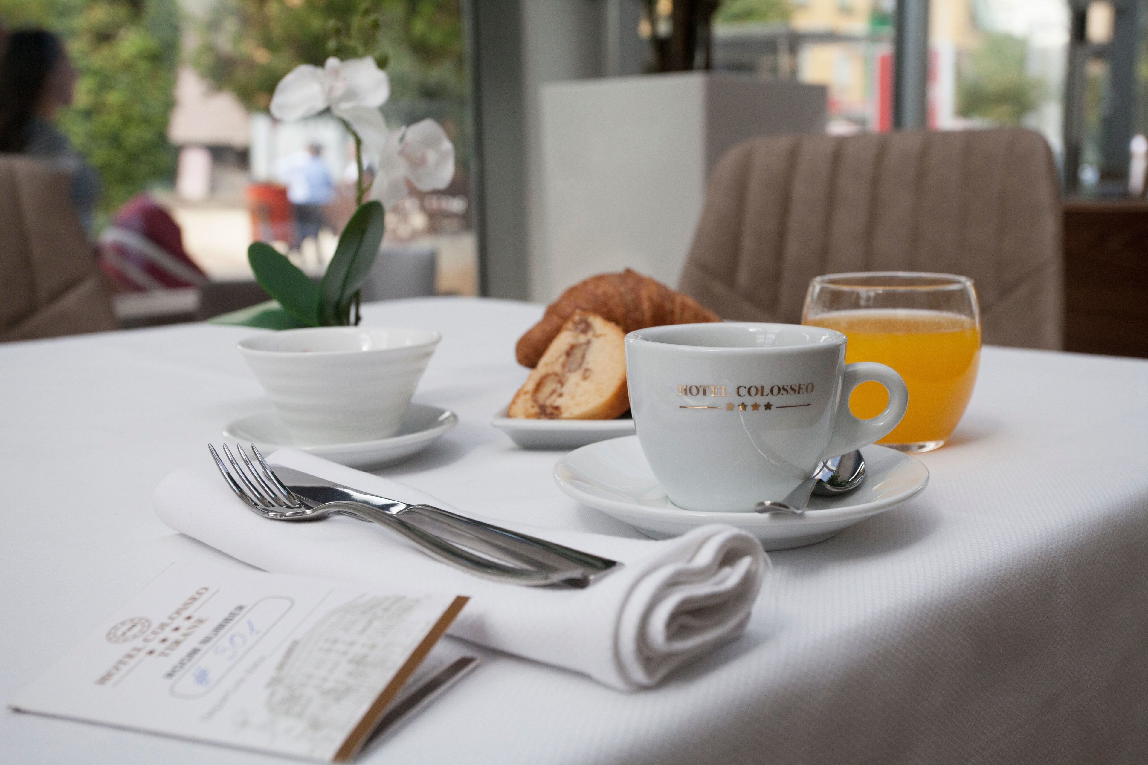 Ein Frühstückstisch mit einem Croissant, einer Kaffeetasse und Orangensaft.