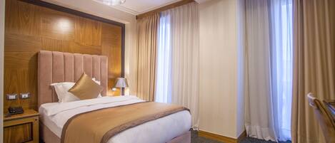 Habitación de hotel con una cama grande, cabecera de madera y una mesita de noche con lámpara.