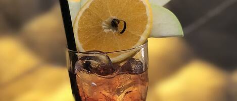 Un grand verre contenant une boisson, des glaçons et une tranche d’orange posée sur le bord.