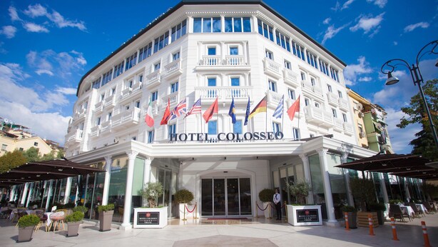 Un hotel con fachada clásica, varias banderas y una entrada central.