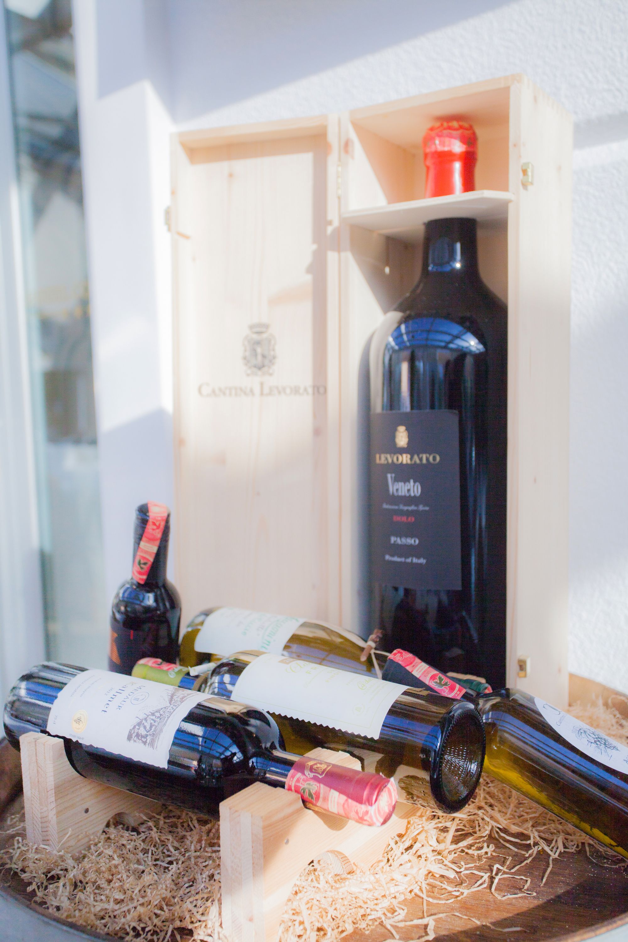 Una caja de madera con botellas de vino, incluyendo una botella etiquetada como “LEVORATO Veneto”.