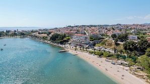 A coastal town with a beach, buildings, and a clear sky.
