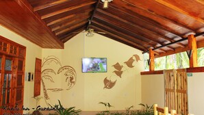 A covered area with a wooden ceiling, a television mounted on the wall, and a heart-shaped mural.