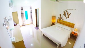 A hotel room with a bed, a wooden headboard, a wall mural, a bedside lamp, and a bathroom visible in the background.