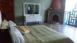 Ein Schlafzimmer mit einem Bett, einem Schminktisch, einem Spiegel und einem Kamin.