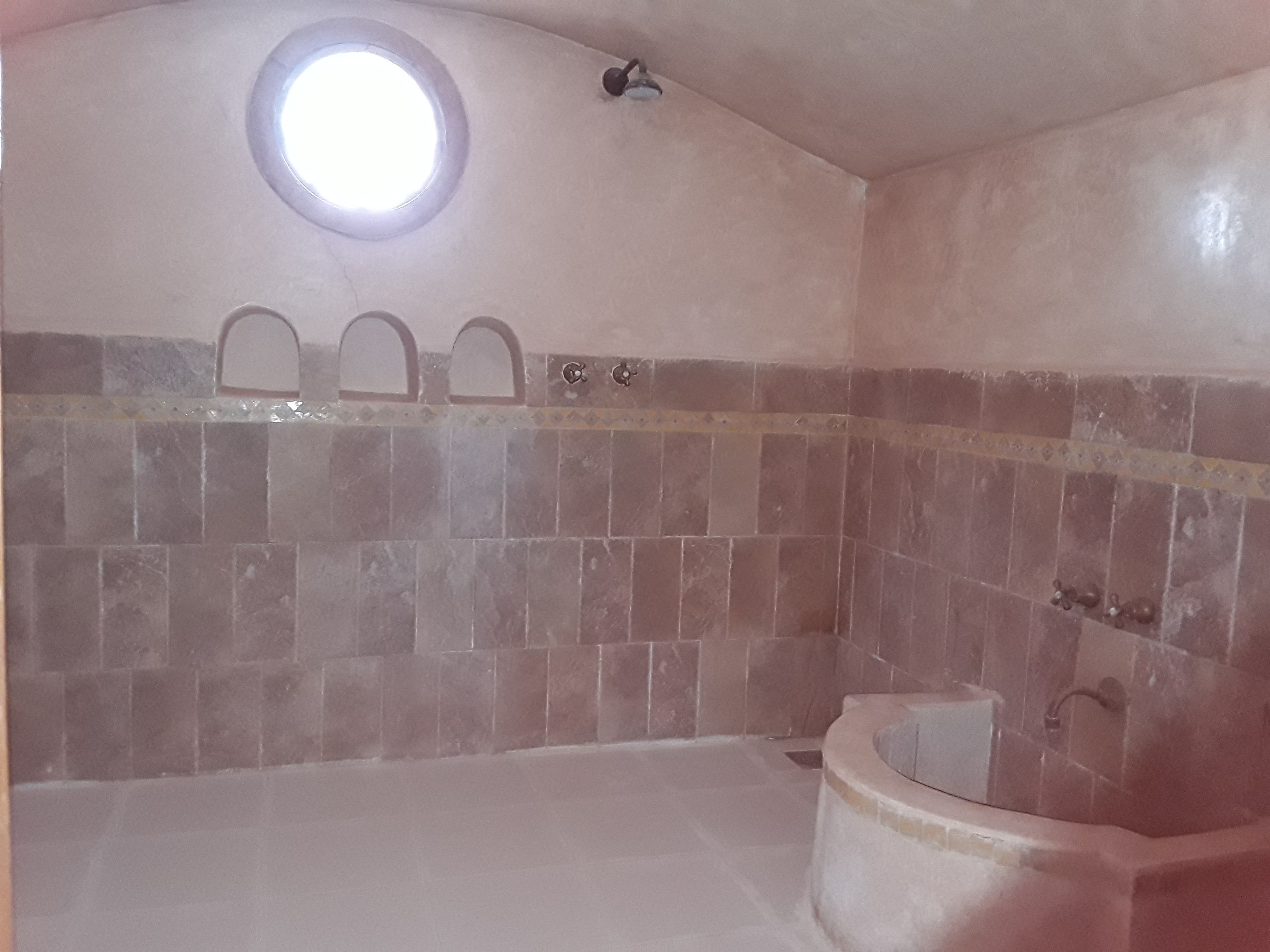 A bathroom with a bathtub, a shower, and a small skylight.