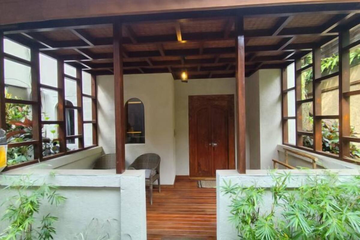 A covered porch with wooden beams, a wooden door, and a chair.