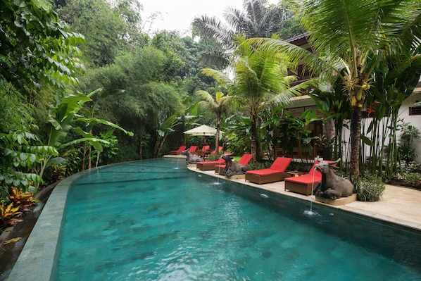 Una piscina al aire libre, sillones reclinables de piscina