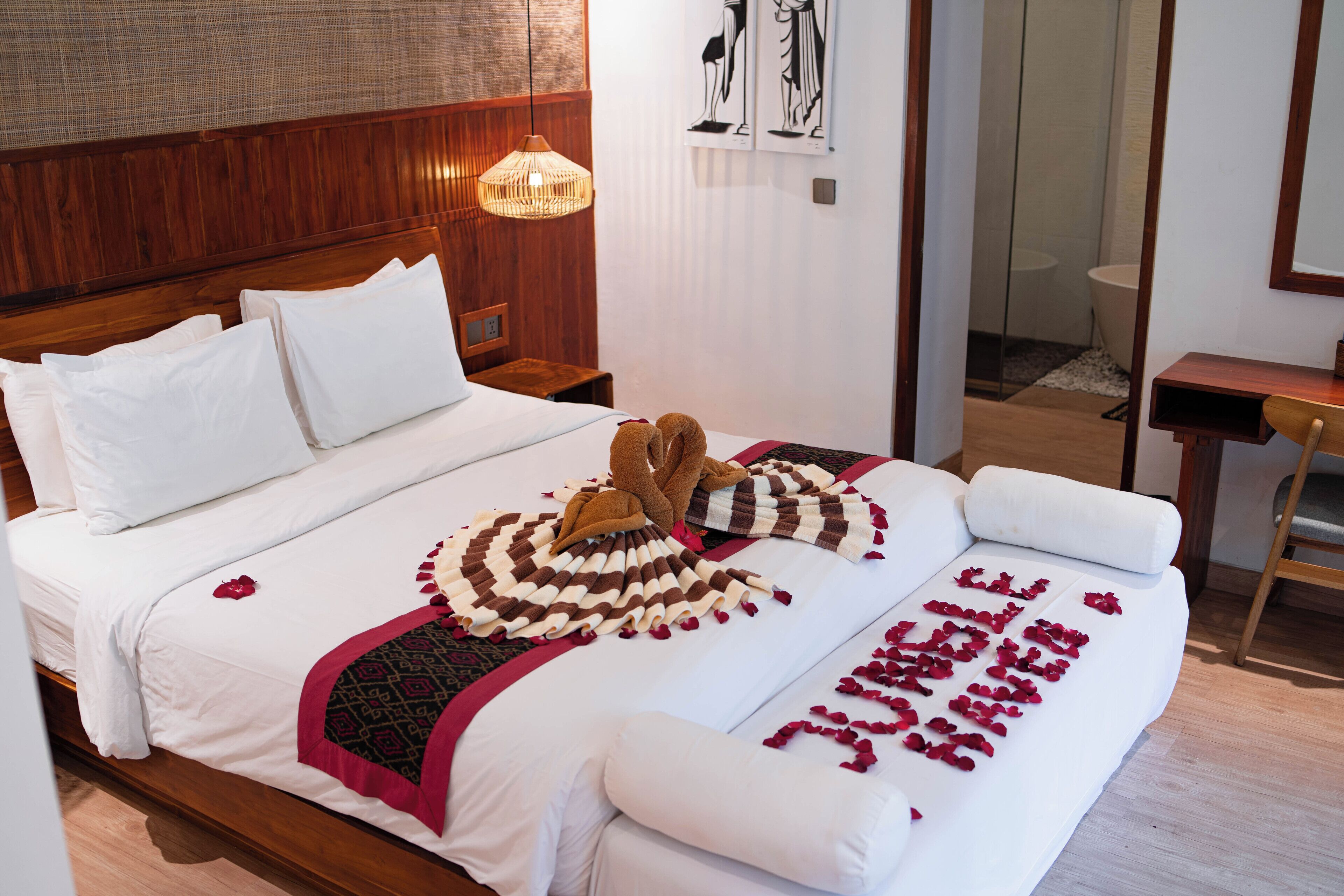 A neatly made bed with a decorative towel and a blanket, a wooden headboard, a bedside table, and a small picture frame.