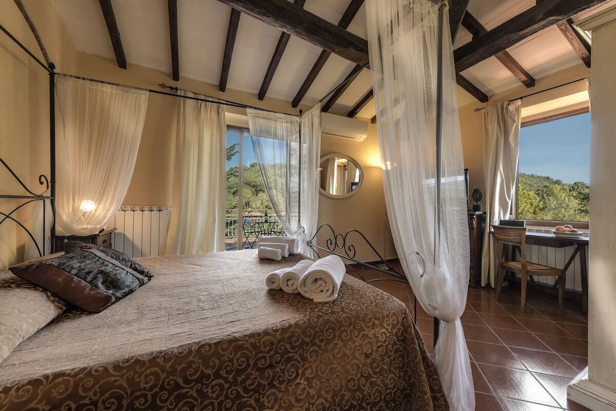 A bedroom with a bed, a desk, and a view of the outdoors.