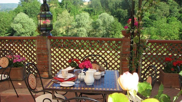 A terrace with a table set for dining, surrounded by a lattice fence and potted plants. - Villa Poggio di Gaville (Figline e Incisa Valdarno)