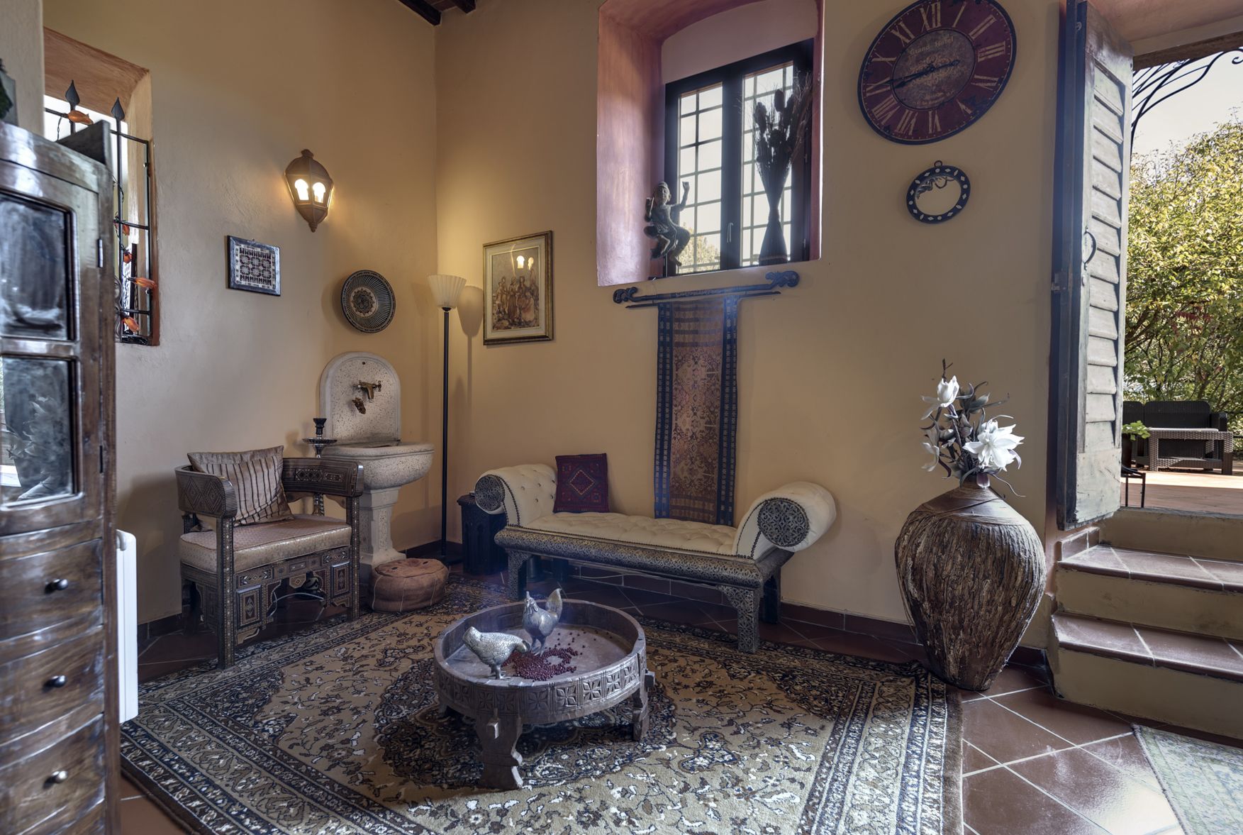 Une pièce chaleureuse au décor traditionnel, comprenant un canapé, une petite table, un vase décoratif et une horloge murale.