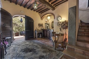 A rustic interior with a wooden door, a stone fireplace, a dining area, and a staircase.