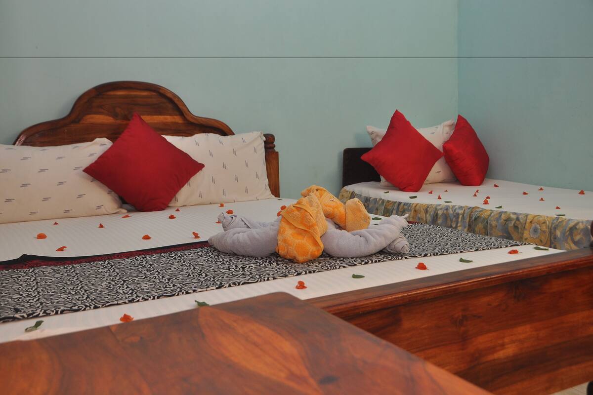 A hotel room with two beds, each with red and patterned pillows, and a wooden headboard.