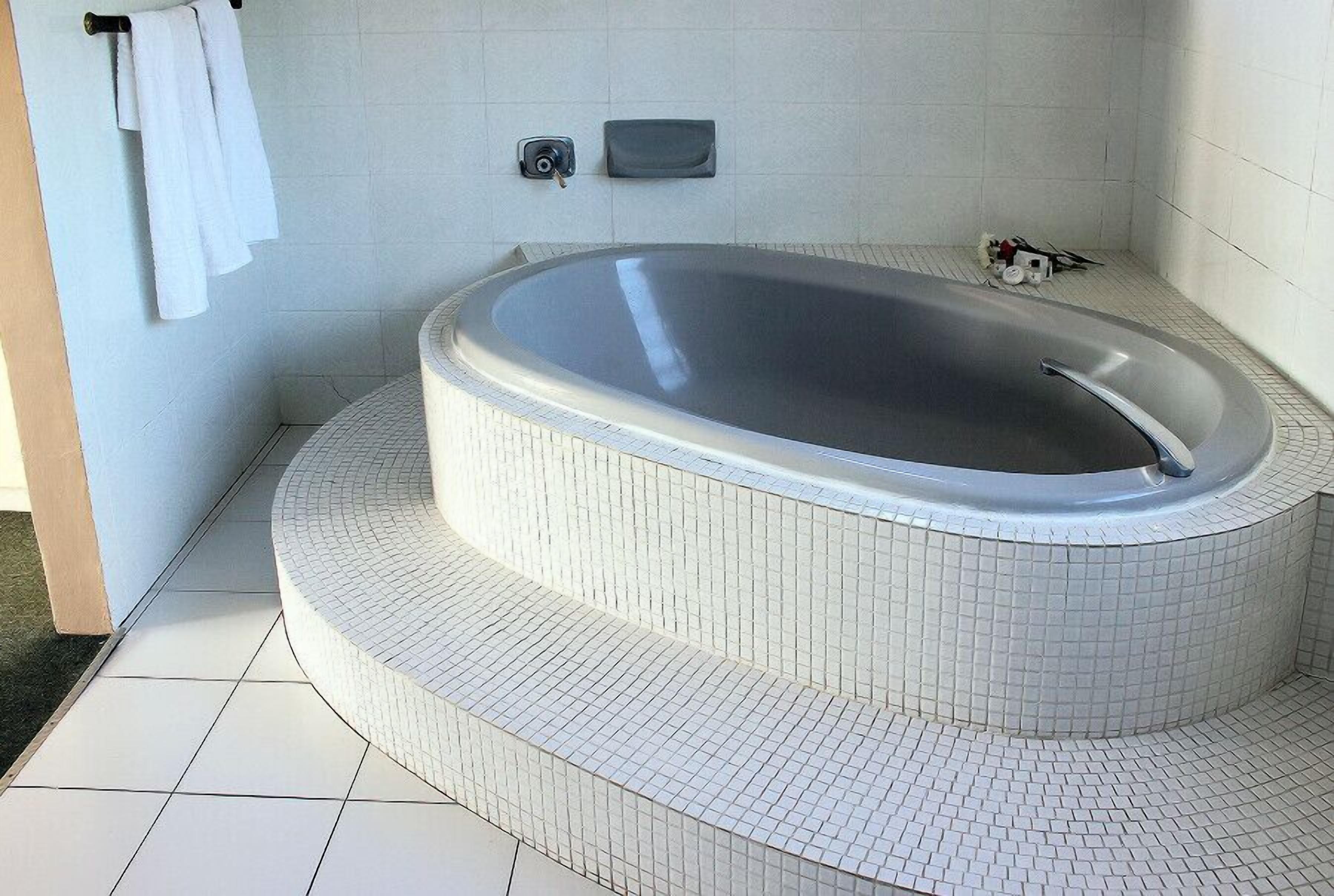 A modern bathroom with a freestanding bathtub, white tiled walls, and a tiled floor.