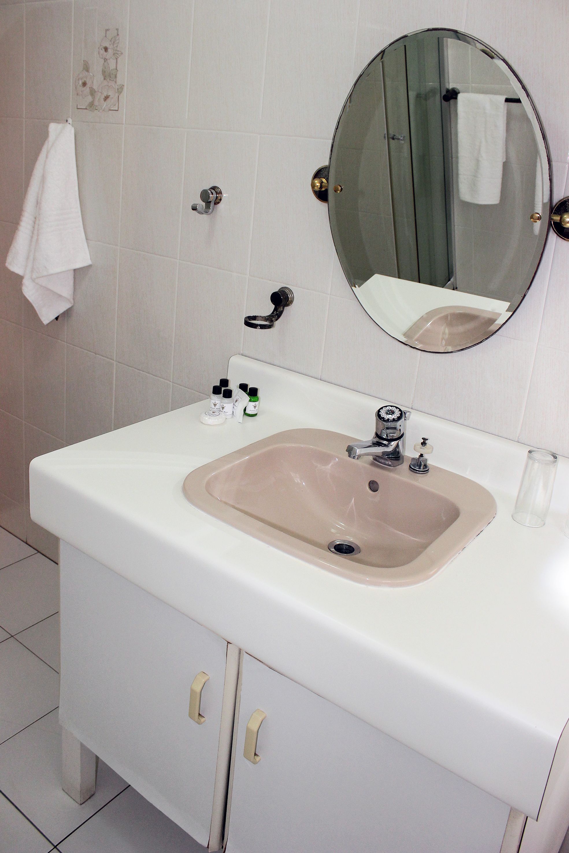 Une salle de bain avec un lavabo blanc, un miroir et un meuble.
