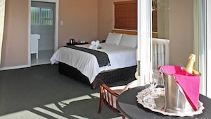 Une chambre d’hôtel avec un lit, une petite table sur laquelle se trouvent une bouteille et des verres, et une vue sur l’extérieur.