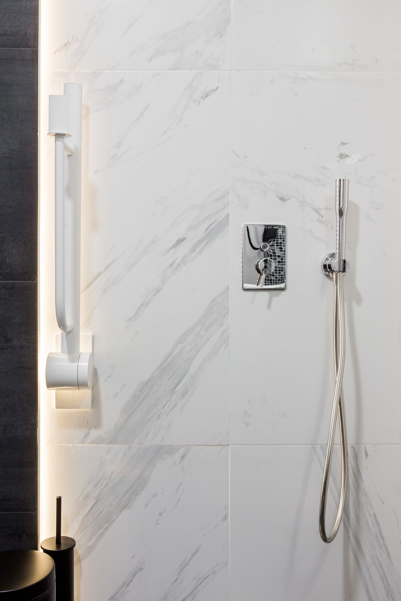 Een moderne badkamer met een marmeren wand, een handdouche en een bedieningspaneel aan de muur.